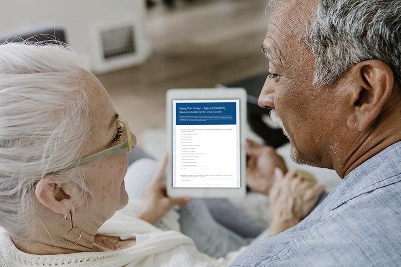 Older adults looking at a digital tablet with the ADRC Aging Survey.