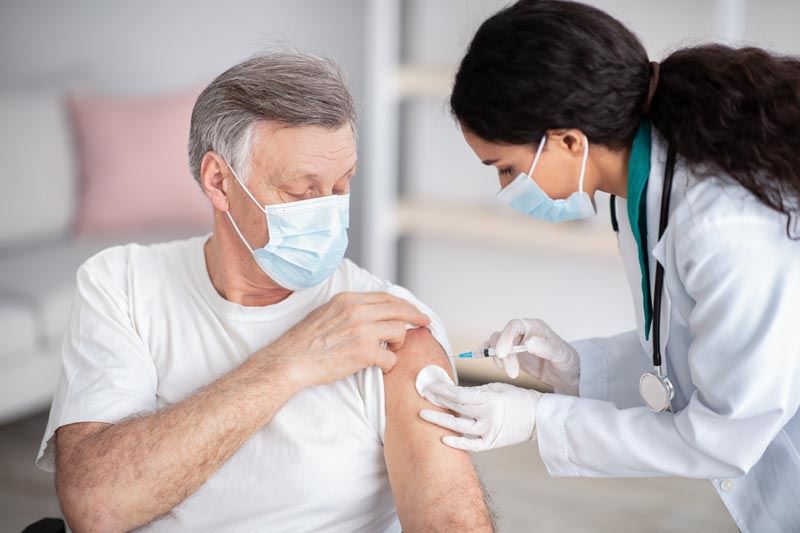 A doctor giving a vaccine to an older man. 