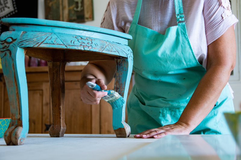 A person painting a vintage piece of furniture. 