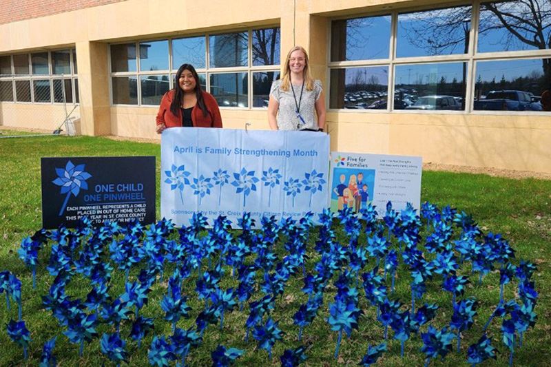 Employees standing by banners and pinwheels set up for family strengthening month.