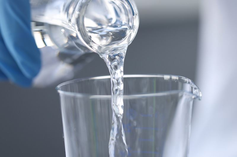 A person pouring water into a beaker.