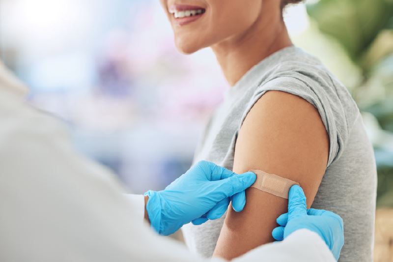 A health professional placing a band aid on a Persons's arm. 