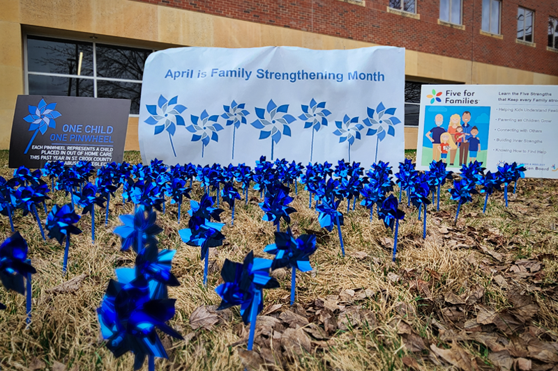 Blue pinwheels and signs highlighting Family Strengthening Month.
